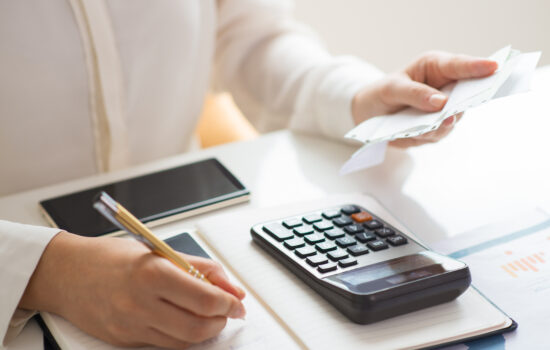 Business professional reviewing invoices and calculating transaction costs